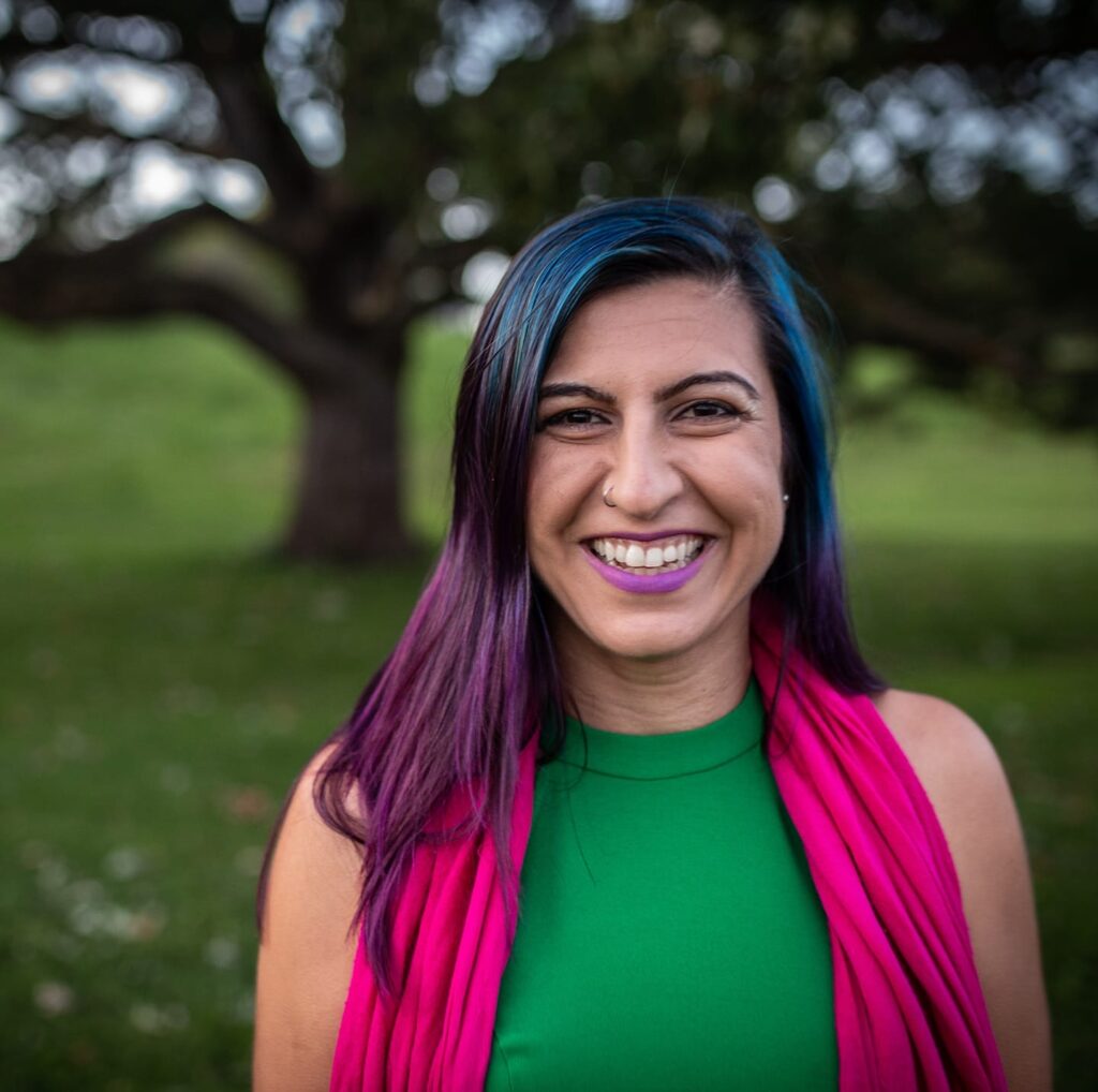 Parastoo Badie in green dress, pink scarf, smiling, in front of thinking tree in Ottawa Canada