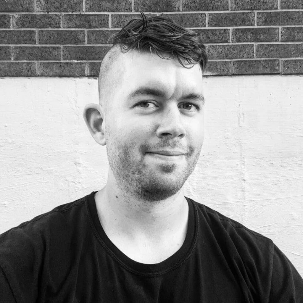 black and white headshot of Paul Hynes in front of a brick wall