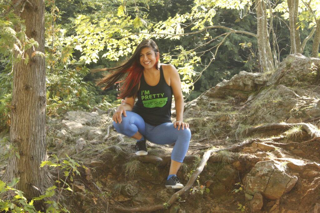 Parastoo kneeling in the woods, with a shirt that says I'm pretty fierce